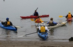 Six sea kayakers floating in the water during beginning kayak instruction.