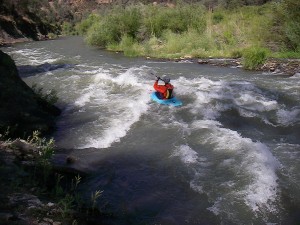 Blue kayak running a rapid.