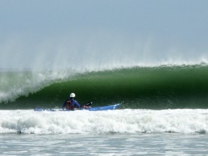 Sea Kayaker facing beautiful green wave.