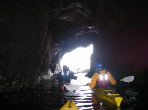 Three kayakers paddling through a cav.