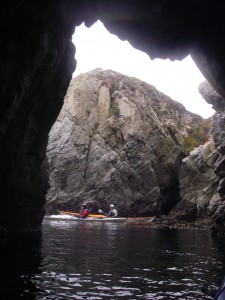 Looking out a cave to two sea kayakers at Pt. Lobos.